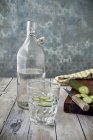 Um copo de água de pepino, uma garrafa de água e pepino fresco — Fotografia de Stock