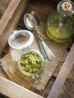 Vista elevada de coentro vegan e salsa Pesto em um frasco em uma superfície de madeira — Fotografia de Stock