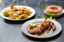 Vista de perto de três pratos de crustáceos com camarão, fruta, anel de camarão e lagosta — Fotografia de Stock