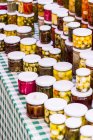 Pickle vegetables in glass jars on a market stand outdoors — Stock Photo