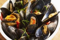 Closeup view of steamed mussels with pepper and dill in bowl — Stock Photo
