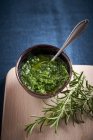 Elevated view of Pesto with rosemary and spoon in a bowl — Stock Photo