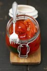 Pickled peppers in a glass jar with a fork on a chopping board — Stock Photo