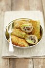 Fried cabbage roulades filled with mushrooms, bacon and millet on plate with fork over towel — Stock Photo