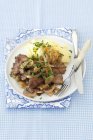 Hígado de pollo con cebolla, champiñones, patata pura sobre plato blanco con tenedor y cuchillo - foto de stock