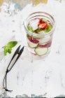 Cucumber and strawberry water with ice cubes  on weathered wooden surface — Stock Photo