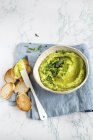 Roasted green asparagus hummus in white bowl over towel with knife — Stock Photo