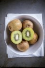 Fresh Kiwis with halves in bowl — Stock Photo