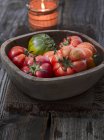 Tomates em tigela de madeira sobre madeira — Fotografia de Stock