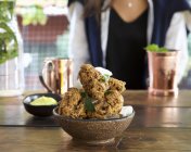 Closeup view of crispy fried chicken with herb and woman on background — Stock Photo