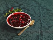 Closeup view of cranberry sauce in bowl and spoon — Stock Photo