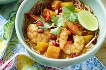 Bowl of prawn Laksa soup with toppings of pomegranate and coriander — Stock Photo