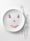 Вид крупным планом розовых конфет в форме улыбающегося лица на белой тарелке — стоковое фото