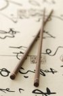 Nahaufnahme zweier chinesischer Essstäbchen auf Papier mit Schriftzügen — Stockfoto