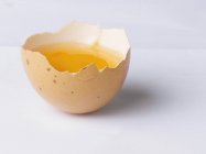 Yema de huevo en la mitad de cáscara de huevo - foto de stock