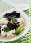 Shiitakes chineses e sopa de bacalhau na placa branca sobre a superfície verde — Fotografia de Stock