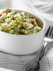 Quinoa tabbouleh in white dish over towel with fork — Stock Photo