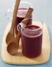 Closeup view of beetroot and zucchini creams in glasses with spoons — Stock Photo
