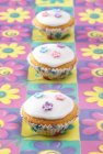 Fairy cakes on coloured flower pattern — Stock Photo