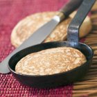 Closeup view of buckwheat blini with frying pan and spatula — Stock Photo