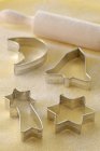 Closeup view of different shaped biscuit cutters and rolling pin on dough — Stock Photo