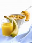 Детский завтрак с бананом, хлопья в миске и сок в стакане — стоковое фото