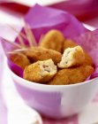 Closeup view of potato Croquettes and toothpicks in paper lined bowl — Stock Photo