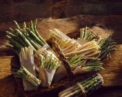 Asparagus wrapped in papers laying on wooden surface — Stock Photo