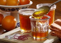Nahaufnahme von hausgemachter Marmelade in Gläsern mit ganzen Orangen auf dem Hintergrund — Stockfoto