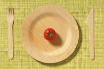 Деревянная тарелка и помидор — стоковое фото