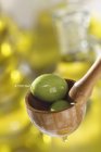 Зеленые оливки в деревянной ложке — стоковое фото