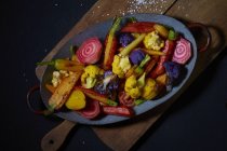 Смажені овочі на синій тарілці над дерев'яним столом — стокове фото
