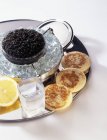 Caviar en soucoupe de verre sur plateau sur surface blanche — Photo de stock