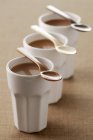Closeup view of chocolate flans with spoons on cups — Stock Photo