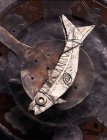 Vue surélevée de la silhouette en forme de poisson sur une vieille écumoire sur plaque — Photo de stock