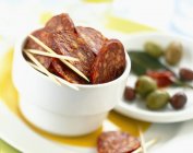 Chorizo and olives in small white bowl — Stock Photo