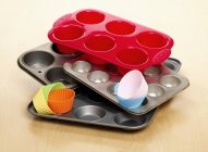 Selection of different types of baking trays and cases for making cupcakes on wooden surface — Stock Photo