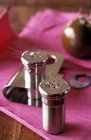 Closeup view of salt and pepper pots with a tomato on pink cloth — Stock Photo