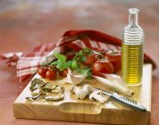 Composición de ingredientes para la receta italiana sobre tabla de cortar de madera con botella y cuchillo - foto de stock
