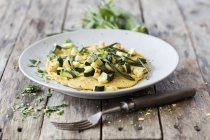 Vegan lupine omelette with zucchini  on white plate on wooden surface with fork — Stock Photo