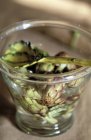 Alcachofras em água em vidro com colher — Fotografia de Stock
