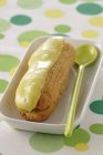 Closeup view of pistachio eclair with green spoon in bowl — Stock Photo
