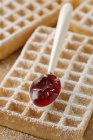 Closeup view of waffles with icing sugar and jam on spoon — Stock Photo
