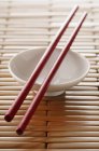 Closeup view of white bowl and red chopsticks — Stock Photo