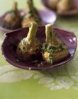 Carciofi la romaine su piatto viola su stoffa verde — Foto stock