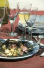 Лучевая рыба с жареным чесноком и каперсы на белой тарелке за столом с очками — стоковое фото
