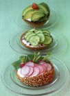Сырые овощи на жареных булочках на стеклянных тарелках над зеленой поверхностью — стоковое фото