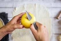 Женщина чистит желтое яблоко — стоковое фото