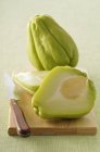 Chayote squashes sloced on chopping board with knife — Stock Photo