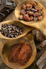 Vista elevada de diferentes formas de cacao en cucharas de madera - foto de stock